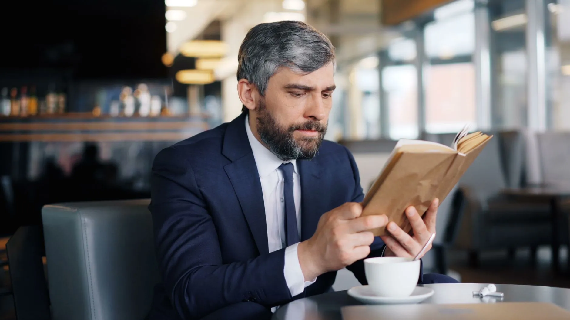カフェで本を読むスーツ姿の男性